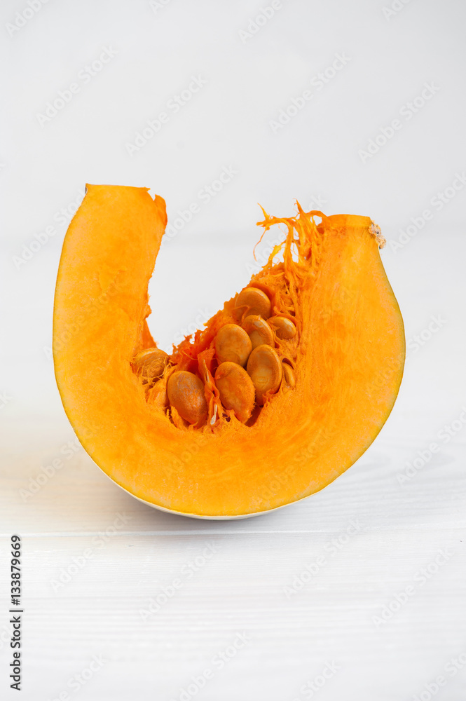 Piece of orange pumpkin on the white wooden table Piece of orange pumpkin on the white wooden table