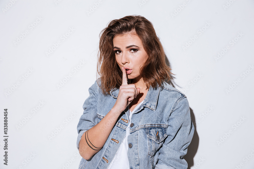 Lady dressed in jeans jacket make silence gesture. Lady dressed in jeans jacket make silence gesture.