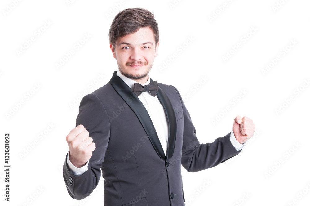 Handsome man wearing tuxedo and bowtie making success gesture Handsome man wearing tuxedo and bowtie making success gesture