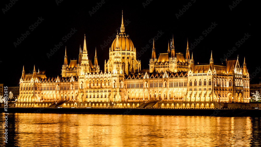 Night view of illuminated historical building of Hungarian Parliament, aka Orszaghaz, with typical symmetrical architecture and central dome on Danube River embankment in Budapest, Hungary, Europe. It