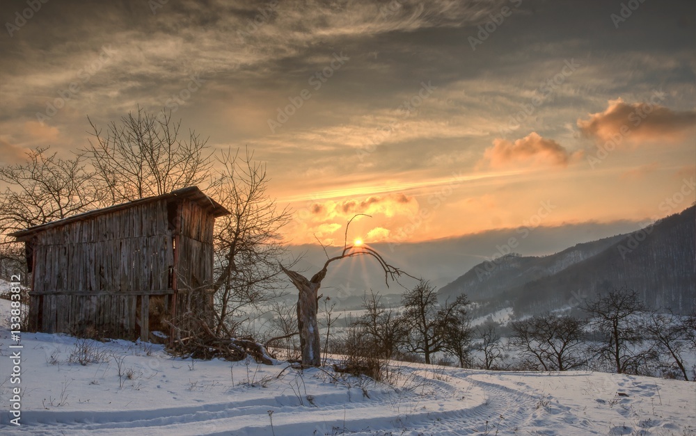 Winter Sunrise Landscape with Old Wooden House and Orange Cloudy Sky