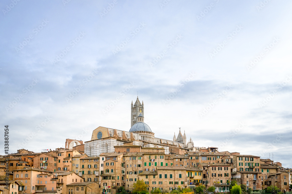 Panoramic view of the historic city of Siena with the cathedral on a cloudy day in Tuscany, Italy.