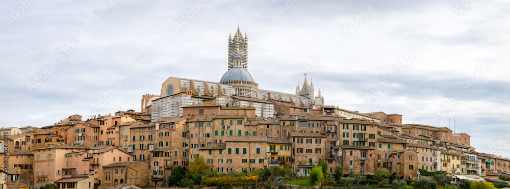 Panoramic view of the historic city of Siena with the cathedral on a cloudy day in Tuscany, Italy.