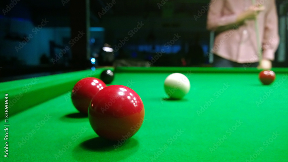 A fragment of the game of Billiards: the position with the balls on the table, and the man standing up, considering further strikes in the game of snooker . Focus on the table