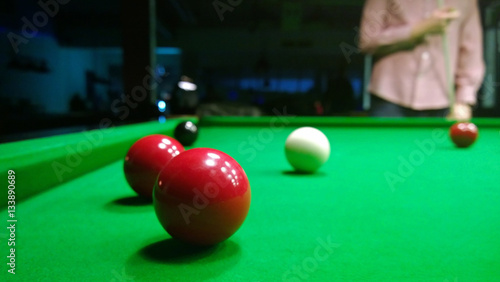 A fragment of the game of Billiards: the position with the balls on the table, and the man standing up, considering further strikes in the game of snooker . Focus on the table