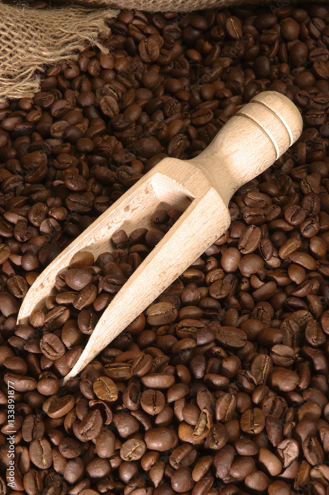 Obraz premium Wooden coffee spoon on background of coffee beans and sackcloth