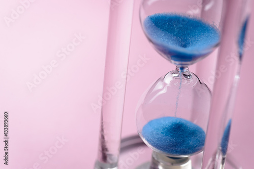 Close-up of hourglass with blue sand pouring