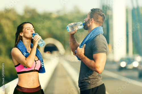 Happy Couple Exercising Outdoors. Drinking Water.