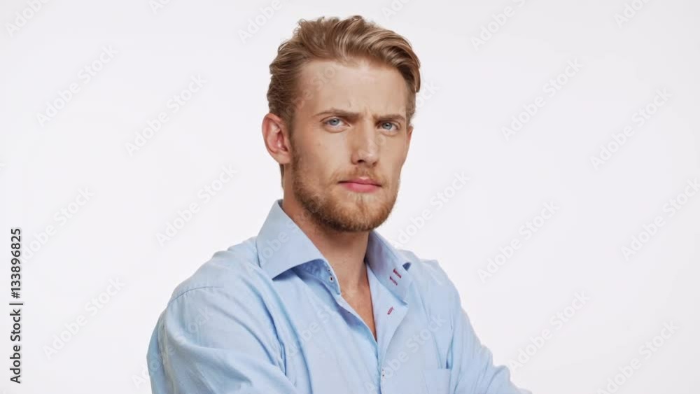 Serious young Caucasian male with blue eyes and brown beard approves on white background Serious young Caucasian male with blue eyes and brown beard approves on white background