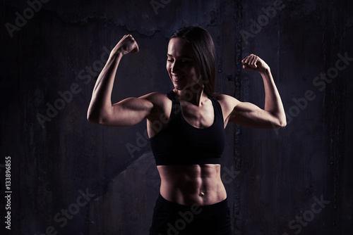 Indoors shot of young confident muscular woman showing the relie © ArtFamily