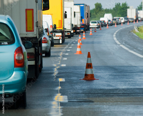 Rear view of rows of traffic queueing on highway with traffic cones