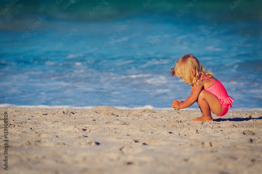 Fototapeta premium cute little girl play with sand on beach