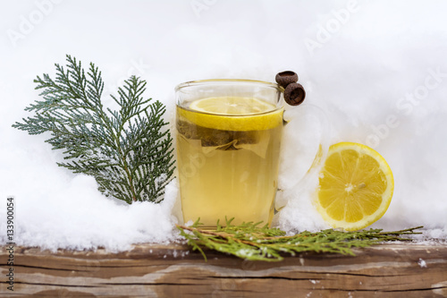 glass cup of tea with lemon slice on the snow