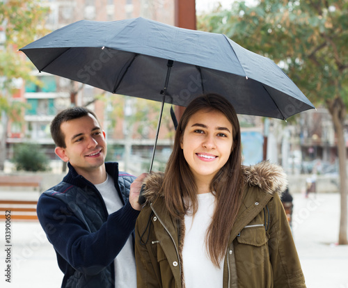 couple walking under umbrella at autumn day