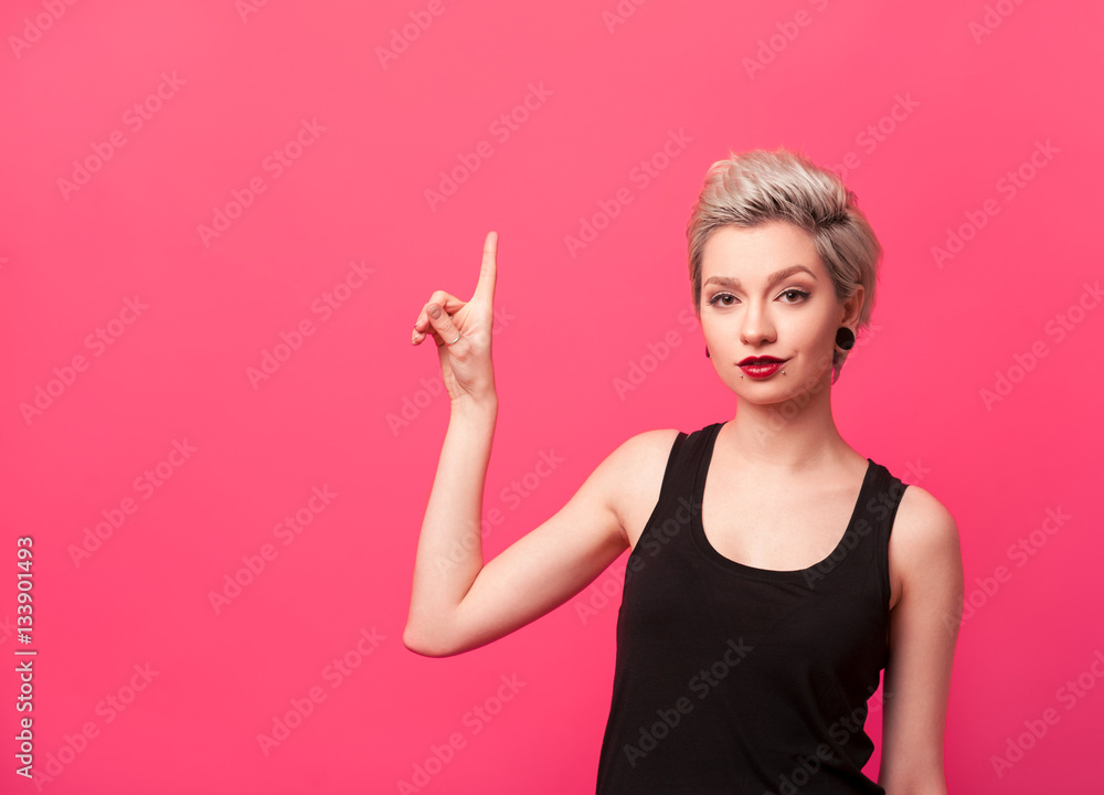 Woman showing up with her finger on pink background. Woman showing up with her finger on pink background.