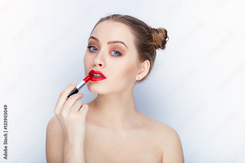 Young pretty woman trendy makeup bright red lips bun hairstyle bare shoulders act the ape with lipstick white studio background Young pretty woman trendy makeup bright red lips bun hairstyle bare shoulders act the ape with lipstick white studio background