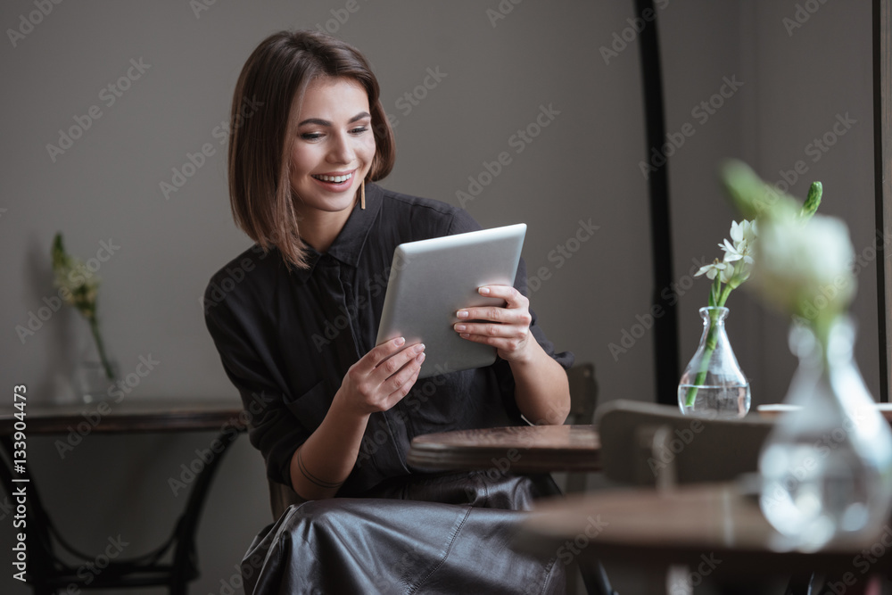 Beautiful woman sitting near window using tablet computer. Beautiful woman sitting near window using tablet computer.