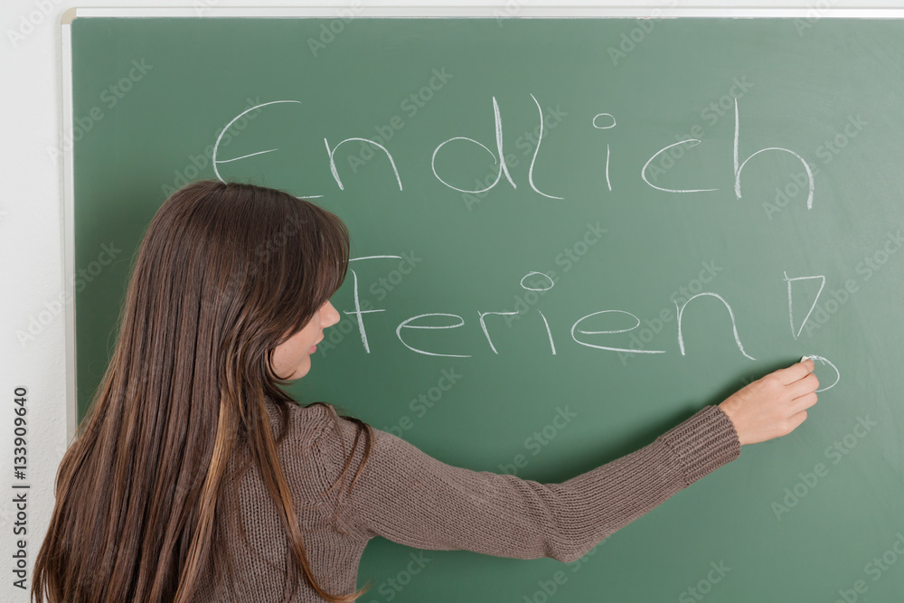 Junges Mädchen vor Schultafel mit dem Spruch Junges Mädchen vor Schultafel mit dem Spruch