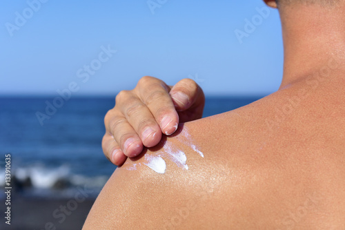 man applying sunscreen to his back