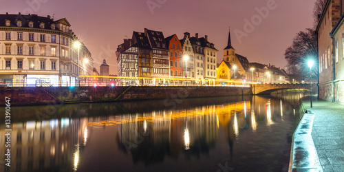 Picturesque panorama of quay and church of Saint Nicolas with mirror reflections in the river Ile during morning blue hour, Strasbourg, Alsace, France