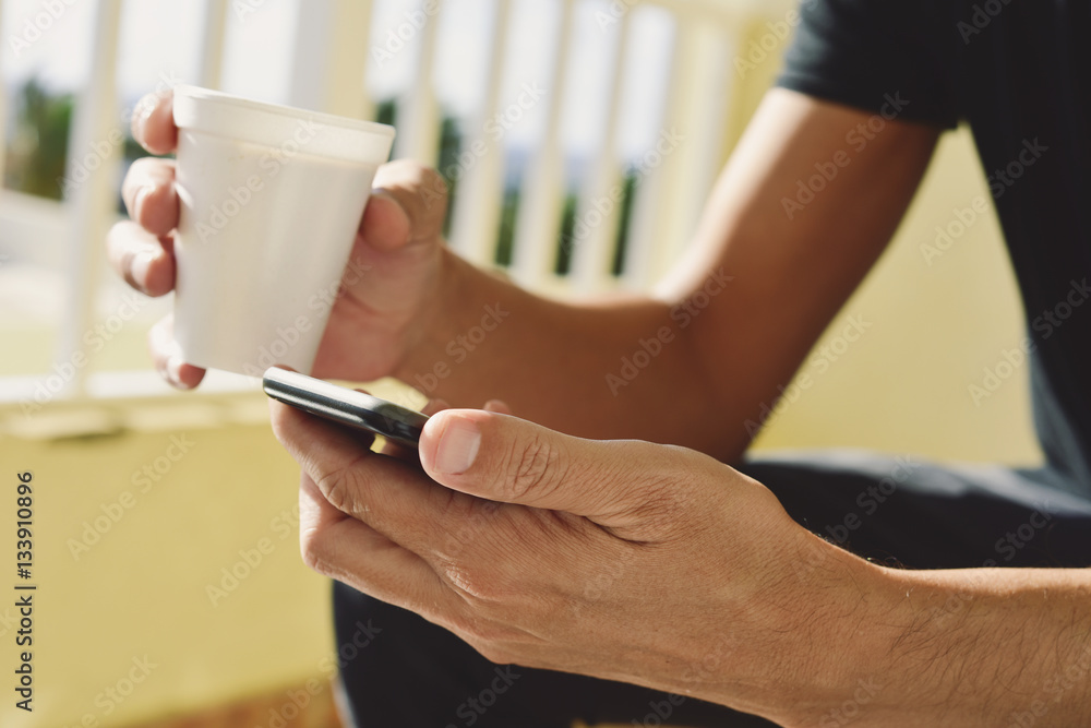young man with a coffee using a smartphone young man with a coffee using a smartphone
