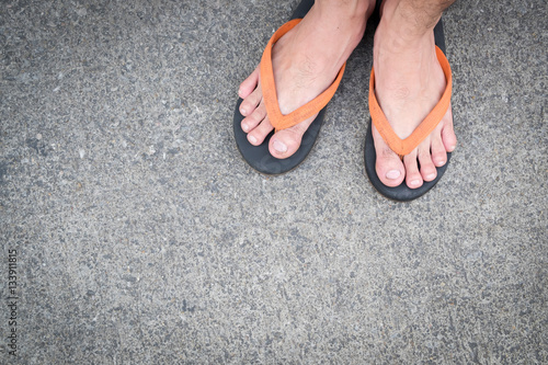 Feet of a man wearing sandals on the old concrete floor.