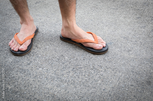 Feet of a man wearing sandals on the old concrete floor. © SAYAN