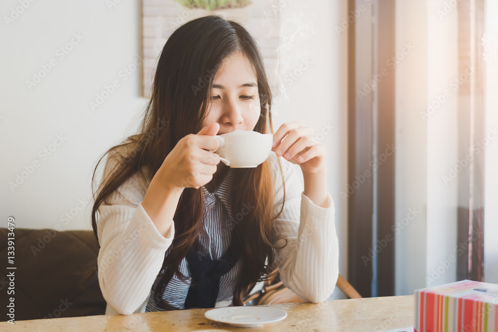 Cute Asia woman drinking coffee with sunrise streaming in through window, vintage tone Cute Asia woman drinking coffee with sunrise streaming in through window, vintage tone