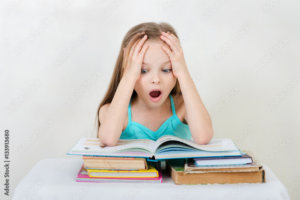 Little girl studying and reading book on light background. . Little girl studying and reading book on light background. .
