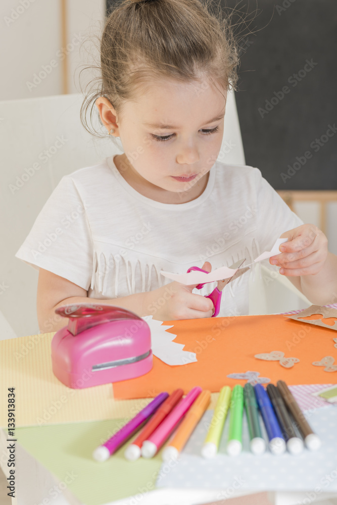 Beautiful little girl cutting paper with scissors on the art lesson class. Children education concept. Kids crafts. Learn Study Education School Knowledge Concept Beautiful little girl cutting paper with scissors on the art lesson class. Children education concept. Kids crafts. Learn Study Education School Knowledge Concept