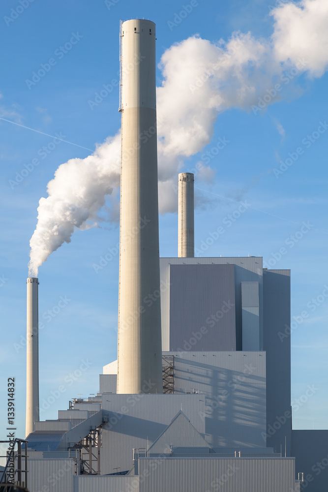 Modernes Kohlekraftwerk mit rauchendem Schornstein vor blauem Himmel Modernes Kohlekraftwerk mit rauchendem Schornstein vor blauem Himmel