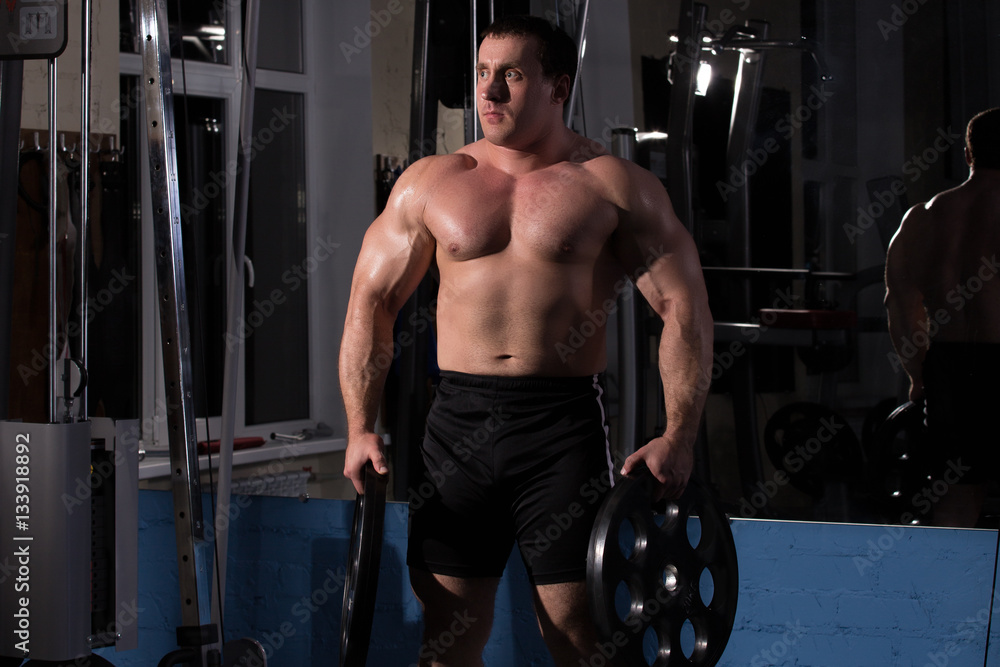 Naklejka premium beautiful, powerful, strong man posing at the gym