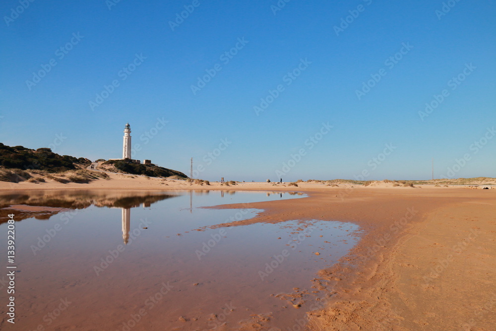 The lighthouse of the Cape of Trafalgar reflected in the water, in the coasts of the south of Spain