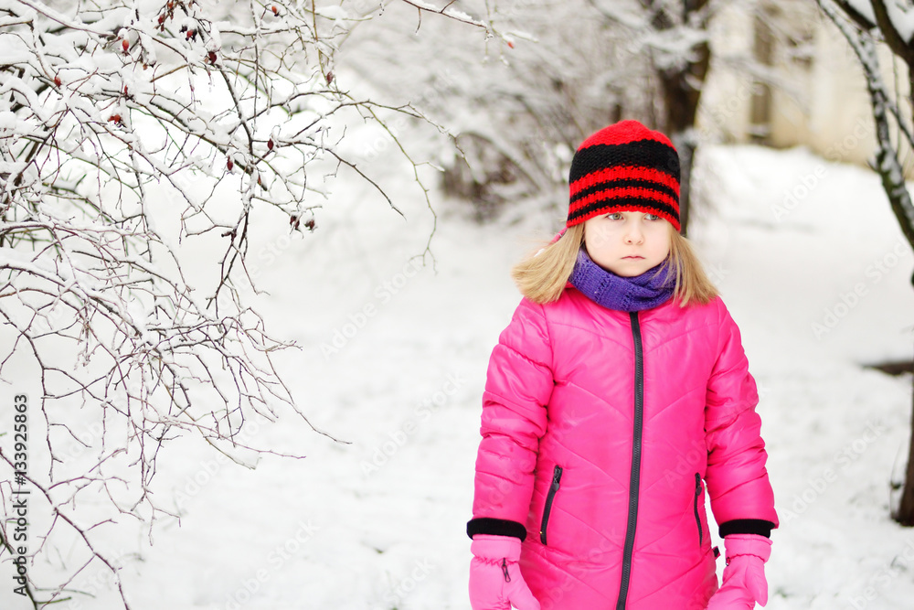 Upset little girl in beautiful winter park during snowfall Upset little girl in beautiful winter park during snowfall