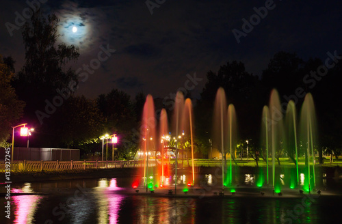 Fountain with backlight on the pond in night park