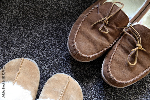 Overhead shot of generic ladies and mens slippers on a dark gray
