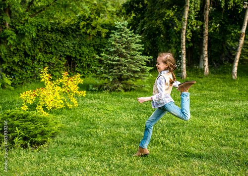 Happy little kid girl jumping on the summer meadow.
