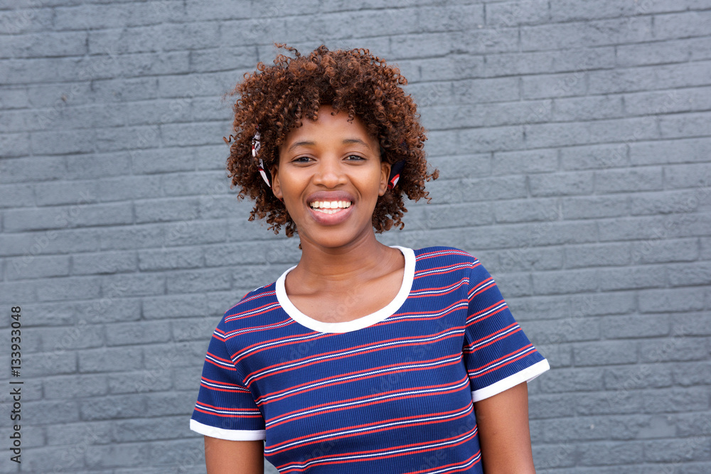 african woman in striped shirt smiling against gray wall african woman in striped shirt smiling against gray wall