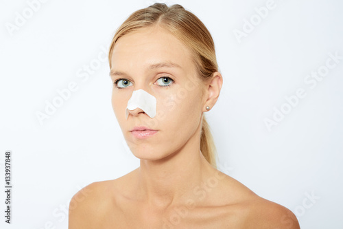 Woman cleaning her face. Beautiful young woman with clear-up pat