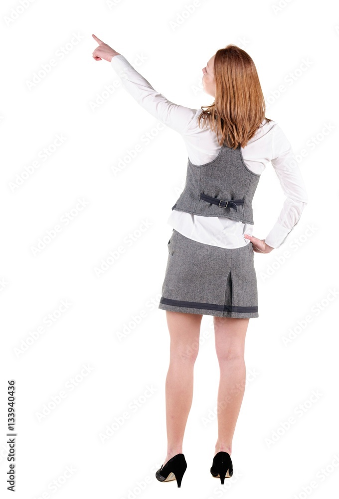 Beautiful young woman in dress pointing at wall. Rear view. Beautiful young woman in dress pointing at wall. Rear view.