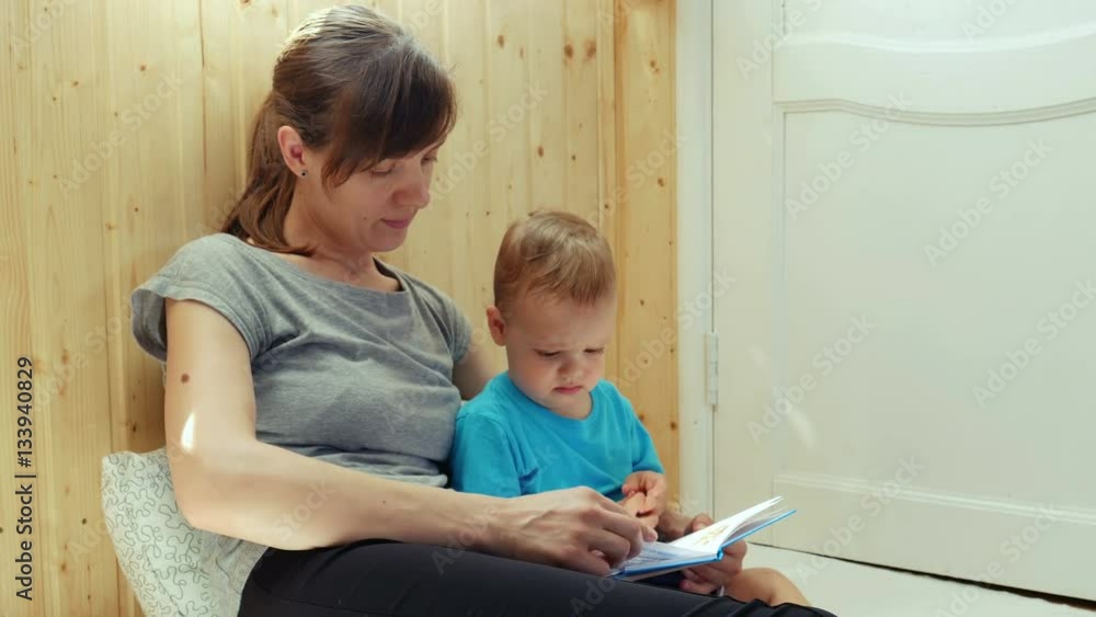 Young mother and her son are reading book. Young mother and her son are reading book.