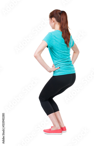 slim girl in sportswear is engaged in sports. She squats.