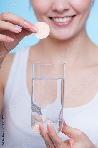 Woman holding glass with water and effervescent tablet