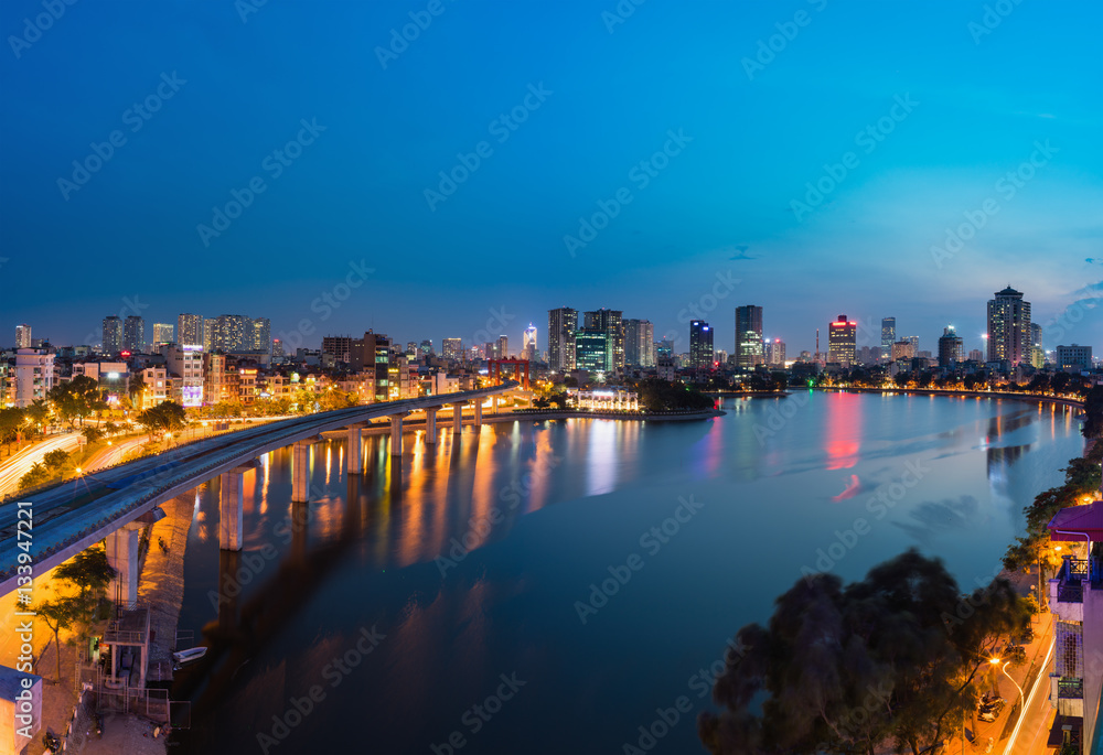 Naklejka premium Aerial view of Hanoi cityscape by twilight period, with Dong Da lake and under construction Cat Linh - Ha Dong elevated railway