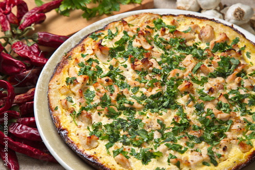 Quiche with chicken, onions, sprinkled parsley.