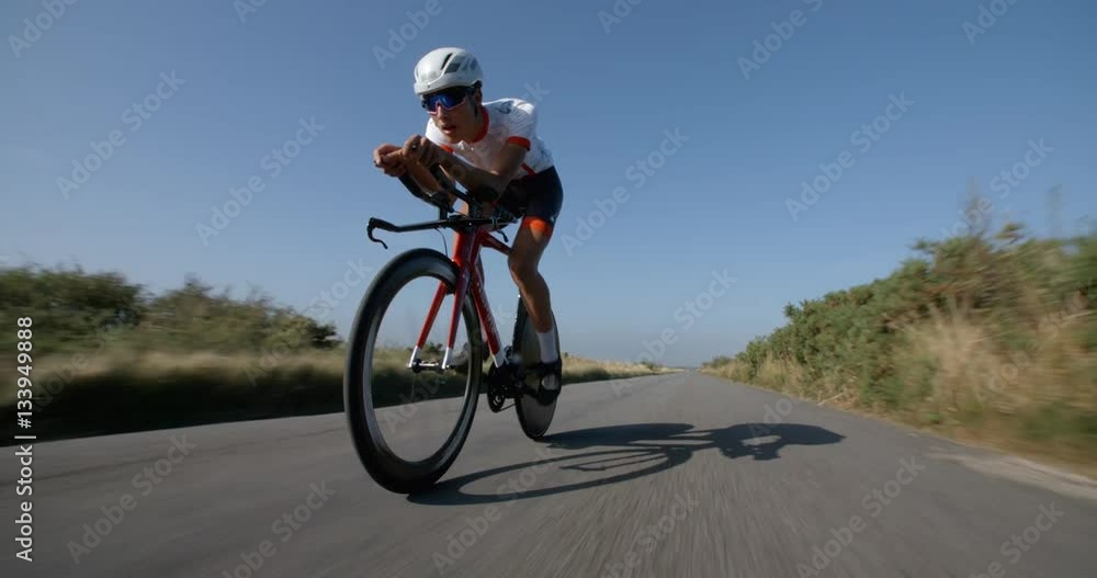 Time trials cyclist peddles along road in Slow Motion. Time trials cyclist peddles along road in Slow Motion.
