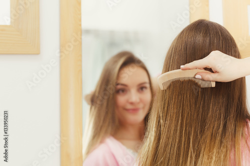 Woman combing her long hair in bathroom