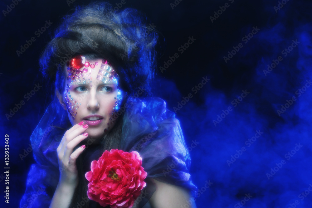 young woman with artistic visage holding big red flower