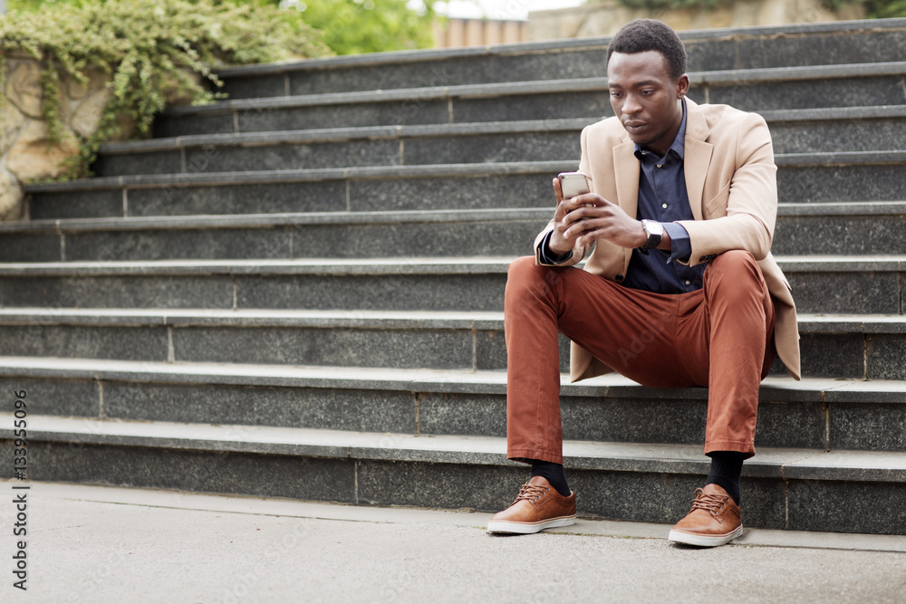 Businessman using smartphone while sitting on steps Businessman using smartphone while sitting on steps
