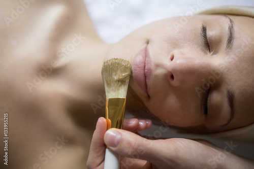 Overhead view of facial mask being applied on woman's face in spa